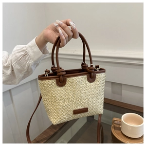 Detail of woven straw handbag with brown leather handles and natural beige texture