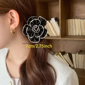 Close-up of a black camellia hair scrunchie with white edges, size 7cm, worn on hair