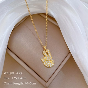 Close-up of gold victory hand pendant with sparkling diamonds on a beige jewelry box