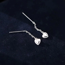 Vue détaillée des boucles d'oreilles cœur en argent S925 sur fond de velours bleu