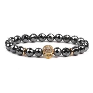 Macro detail of faceted black hematite beads with a gold pavé skull charm on a bracelet