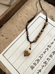 Macro detail of Buddhist prayer beads with a carved lotus pendant on a calligraphy background