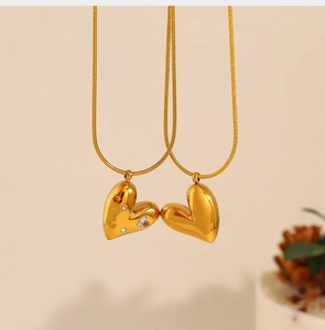 Detailed view of dual 18K gold heart pendants on snake chain with pavé diamonds