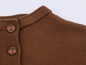 Detail of dark brown knit top featuring ribbed round neck and two round buttons