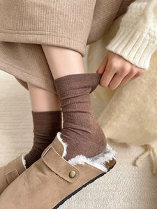 Close-up of ribbed brown cotton socks worn with cozy lined suede mule slippers