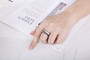 Detail view of a minimalist silver steel ring with black groove line worn on finger