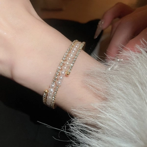 Detail of elegant gold wrap bracelet with rows of white pearls and sparkling pavé crystals