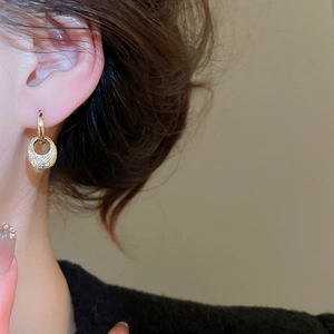 Detail shot of textured gold oval drop earrings with shimmering micro-beaded surface