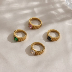 Detailed view of four gold rings with vertical stripes and colorful square gemstones