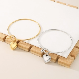 Detail of gold and silver heart pendant bracelets displayed on a wooden stand