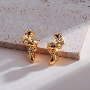 Detailed macro shot of golden twisted double-layer water drop earrings on silk