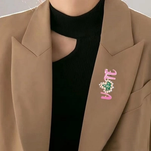 Close-up of pink enamel LOVE brooch with green heart and pearls on a blazer lapel
