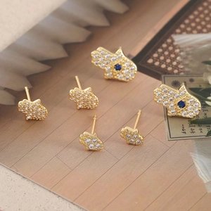 Elegant Hamsa hand stud earrings with sparkling white zircons and blue stones in gold finish