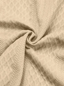 Detailed macro view of beige jacquard knit fabric with waffle and diamond texture