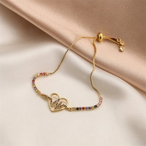 Detail of gold heartbeat bracelet with colorful round zircons on champagne satin