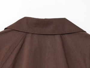 Detail of double-stitched collar and shoulder seams on dark brown trench coat