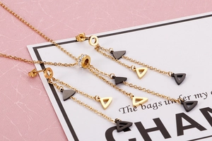 Detailed view of geometric triangle tassel necklace and earrings set with crystal inlay