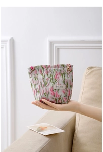 Close-up of floral fabric cosmetic bag with gold flower zipper pull and textured finish