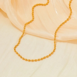 Elegant gold stainless steel oval bead chain necklace on soft yellow silk background