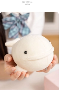 Close-up of a soft white plush beluga whale toy being held by hands as a cozy gift