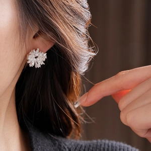 Détail macro de boucles d'oreilles fleurs en argent avec cristaux et une perle centrale