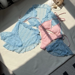 Flat lay of four-piece bikini set with pink rib fabric and blue lace cover-up details
