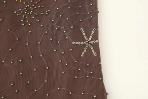 Dettaglio del tessuto a rete con perline metalliche e paillette a forma di stella