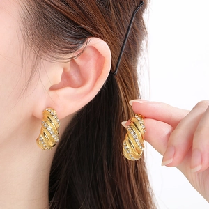 Detailed macro view of gold spiral C-shaped earrings with micro-set sparkling crystals