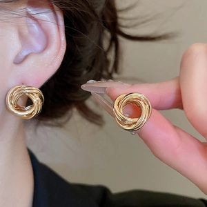 Gros plan de boucles d'oreilles créoles dorées avec un design multi-anneaux ajouré