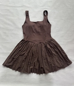 Flat lay detail of brown pleated tennis dress with racerback and elastic sport fabric