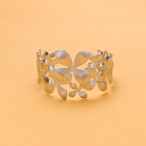 Detail of silver matte flower link bracelet with floral hollow design on orange background