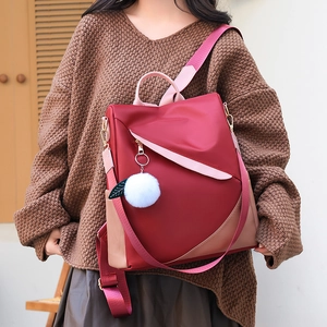 Waterproof burgundy patchwork backpack for women with a white pompom charm accessory