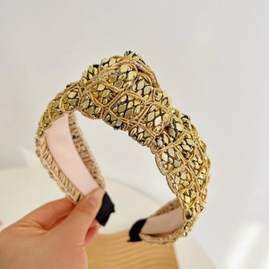 Close-up of a wide knotted headband with gold square studs and pink lining detail