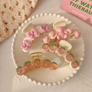Pink peach hair claw clip set with cute heart and bear designs on a ceramic plate