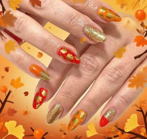 Close-up of almond-shaped press-on nails with maple leaf patterns and gold glitter