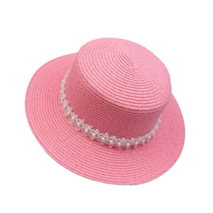Detail of pink straw sun hat with white faux pearls and delicate lace flower trim