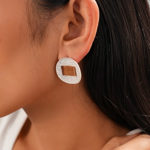 Detail of silver oval earring with brown rectangular inlay worn by model
