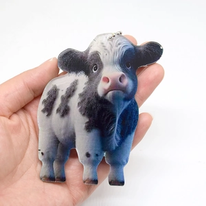 Close-up of a realistic acrylic cow pendant with metal bead chain held in hand