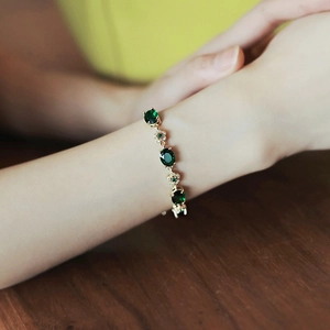 Bracelet élégant plaqué or avec cristaux vert émeraude et accents floraux en zircone