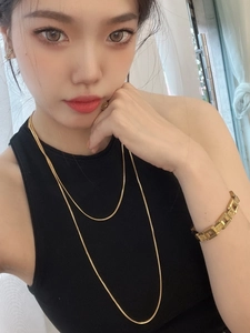 Detail view of 18K gold-plated double-layer snake bone chain and geometric link bracelet