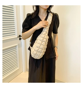 Détail d'un sac nuage matelassé beige avec larges bretelles plissées et texture en nylon