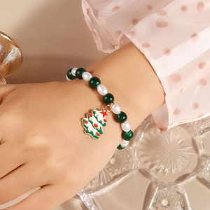 Close-up of Christmas beaded bracelet with green beads and enamel tree charm on wrist