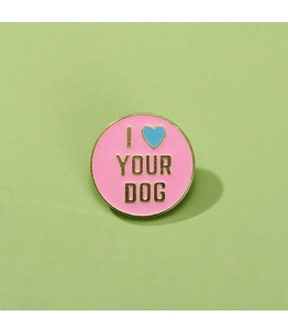Macro detail of round pink enamel pin with I Heart Your Dog text on green background