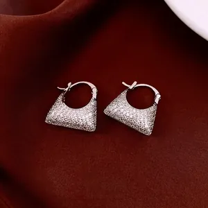 Elegant vintage zircon bag-shaped huggie earrings on premium deep red silk background