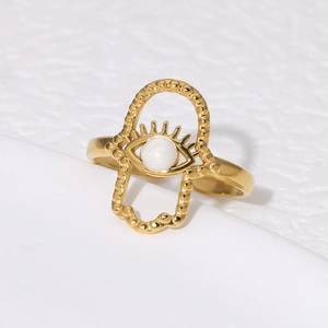 Gold-plated Hamsa Hand and Evil Eye open ring with a white pearl on a white surface