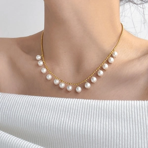 Detail of elegant gold double-layer necklace with hanging white pearls on clavicle chain