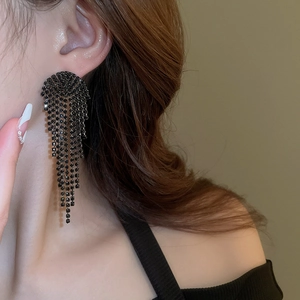 Close-up of model wearing black long tassel drop earrings with sparkling rhinestones