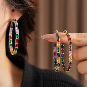 Macro shot of large golden hoop earrings with colorful rainbow cubic zirconia crystals