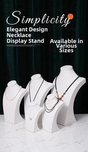 Five white matte necklace display busts in different sizes on green velvet background