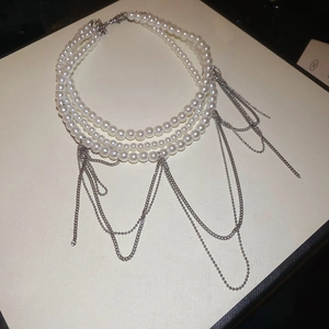 Détail du collier de perles multicouche avec d'élégantes pampilles en chaîne argentée